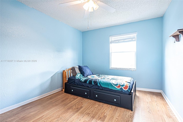 bedroom with ceiling fan, light hardwood / wood-style floors, and a textured ceiling