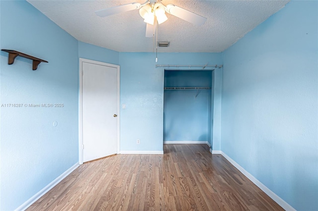 unfurnished bedroom with a closet, a textured ceiling, hardwood / wood-style flooring, and ceiling fan