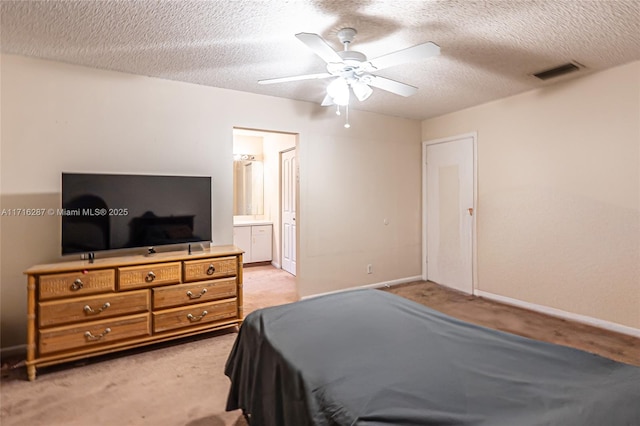 bedroom with ceiling fan, ensuite bathroom, a textured ceiling, and light carpet