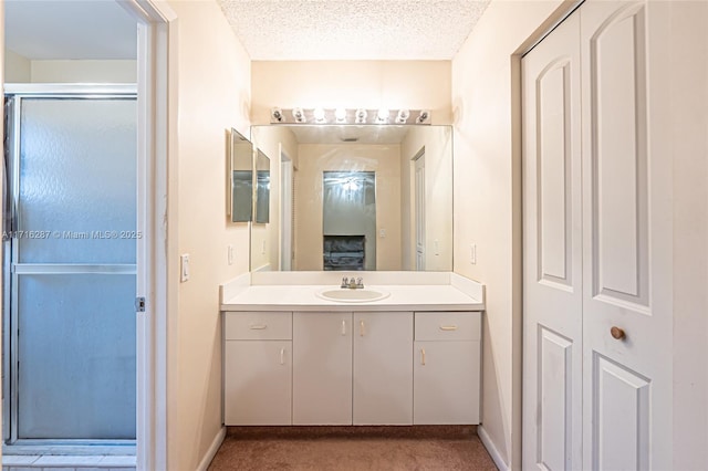 bathroom with vanity, a textured ceiling, and a shower with shower door