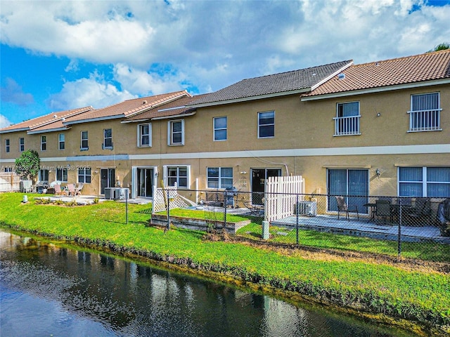 rear view of house featuring a yard, a water view, and cooling unit