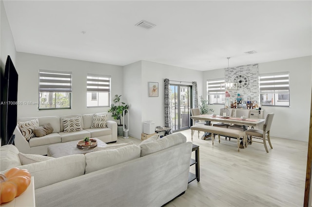 living room featuring light wood-type flooring and an inviting chandelier