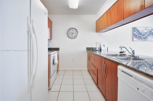 kitchen featuring light tile patterned floors, white appliances, dark stone counters, and sink