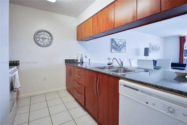 kitchen featuring sink, dark stone countertops, white dishwasher, light tile patterned floors, and range