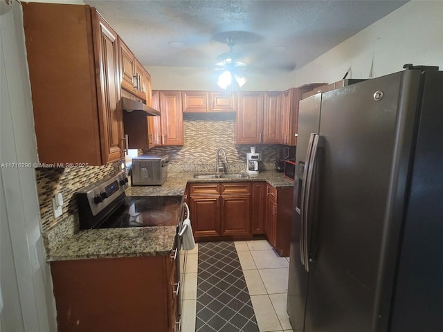 kitchen featuring light stone countertops, sink, ceiling fan, stainless steel appliances, and decorative backsplash