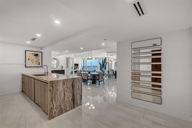 kitchen featuring brown cabinets, visible vents, a chandelier, and a sink