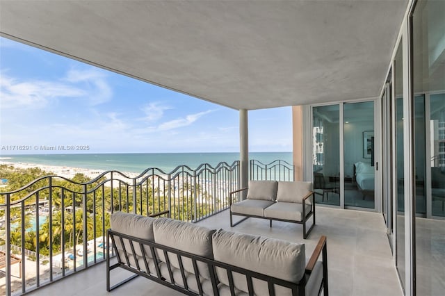 balcony with a water view, an outdoor hangout area, and a view of the beach