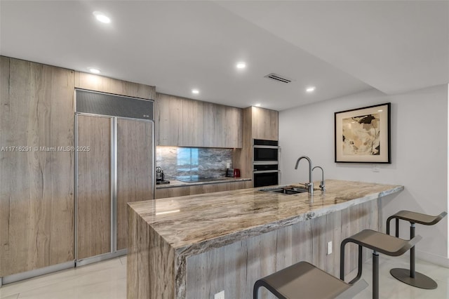 1500 Ocean Dr Unit 1003, Miami Beach, FL 33139 - kitchen featuring paneled built in fridge, light stone counters, a sink, double wall oven, and a breakfast bar