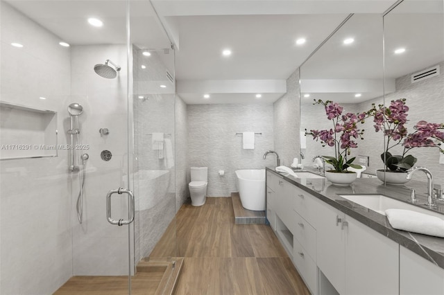 full bathroom featuring vanity, toilet, tile walls, and independent shower and bath