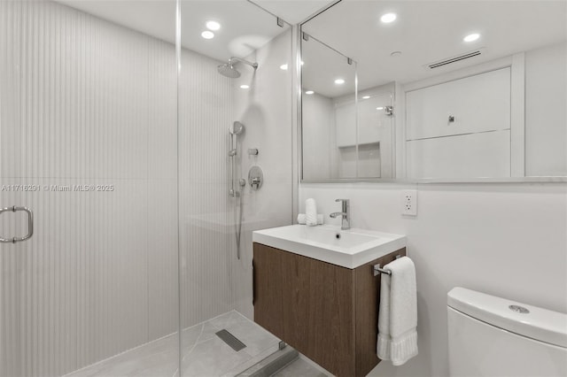 bathroom featuring vanity, toilet, and a shower with door