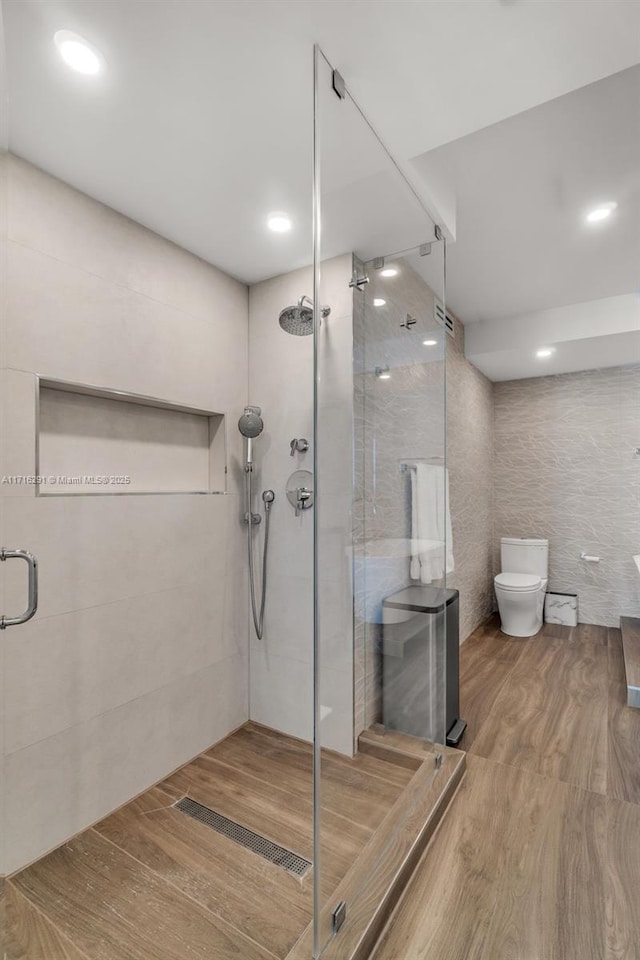 full bathroom featuring tile walls, visible vents, toilet, a shower stall, and wood finished floors