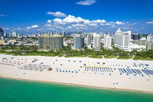 drone / aerial view featuring a view of city, a water view, and a beach view