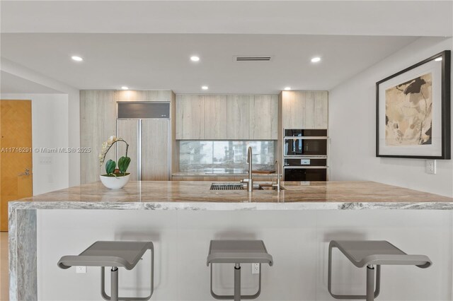 1500 Ocean Dr Unit 1003, Miami Beach, FL 33139 - kitchen featuring dobule oven black, a sink, a breakfast bar area, modern cabinets, and visible vents