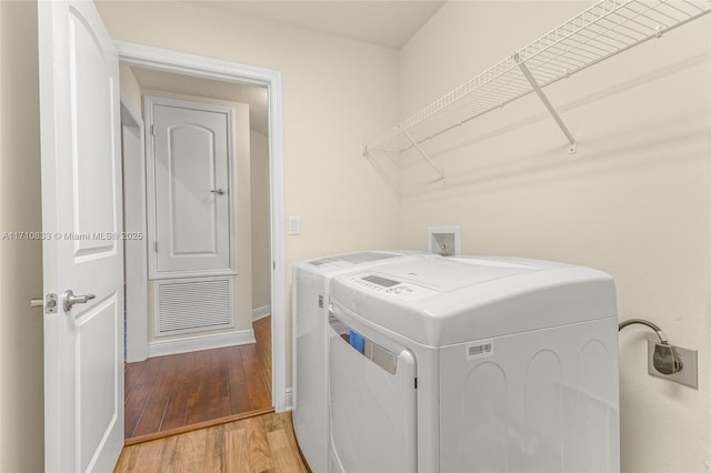 clothes washing area featuring washing machine and dryer and hardwood / wood-style floors