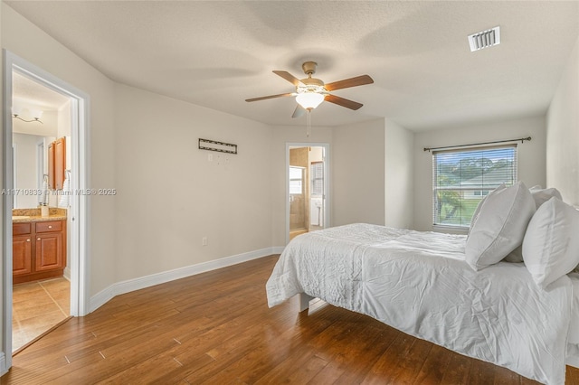 bedroom with hardwood / wood-style flooring, ensuite bathroom, ceiling fan, and multiple windows