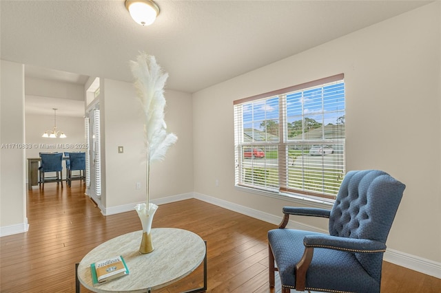 sitting room with hardwood / wood-style floors and an inviting chandelier