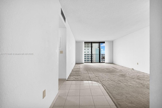 tiled spare room with a wall of windows and a textured ceiling