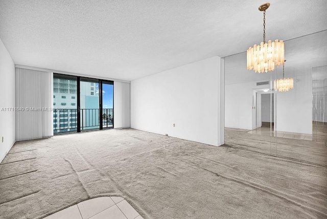 carpeted empty room featuring expansive windows, a textured ceiling, and an inviting chandelier