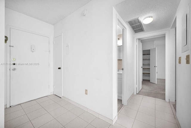 corridor with light tile patterned floors and a textured ceiling