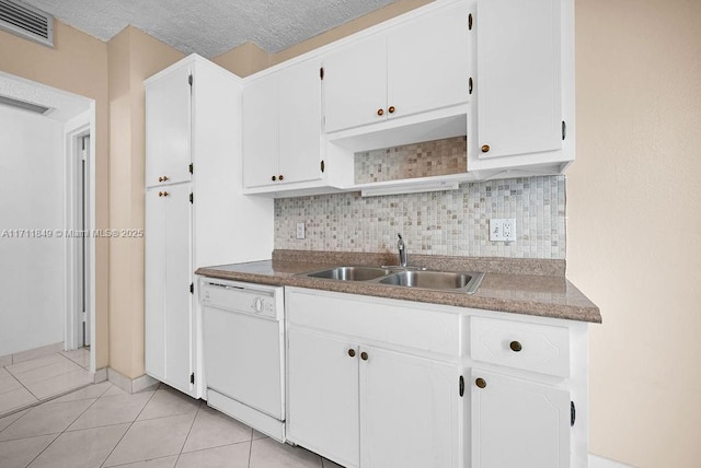 kitchen featuring white dishwasher, sink, light tile patterned floors, a textured ceiling, and white cabinetry