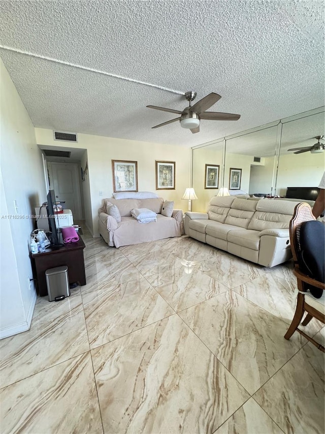 living room featuring ceiling fan and a textured ceiling