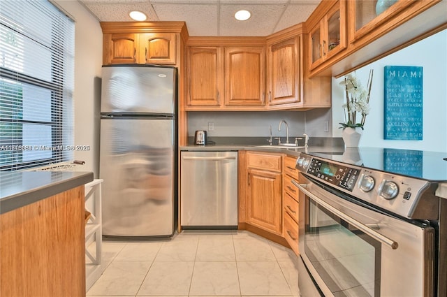 kitchen featuring sink, light tile patterned floors, a drop ceiling, and appliances with stainless steel finishes