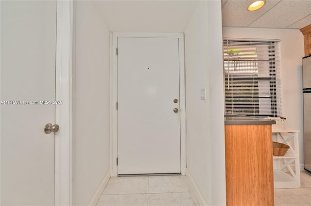 doorway to outside featuring a paneled ceiling and light tile patterned flooring