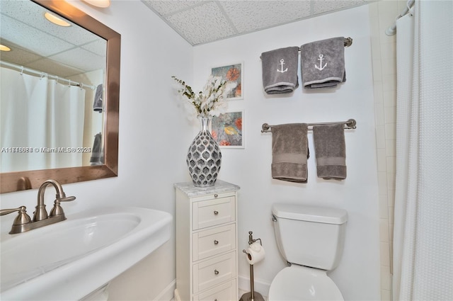 bathroom with a paneled ceiling, a shower with curtain, toilet, and sink