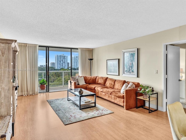 living room with light hardwood / wood-style floors, a textured ceiling, and a wall of windows