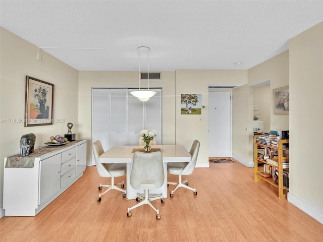 dining space featuring light hardwood / wood-style floors and a textured ceiling