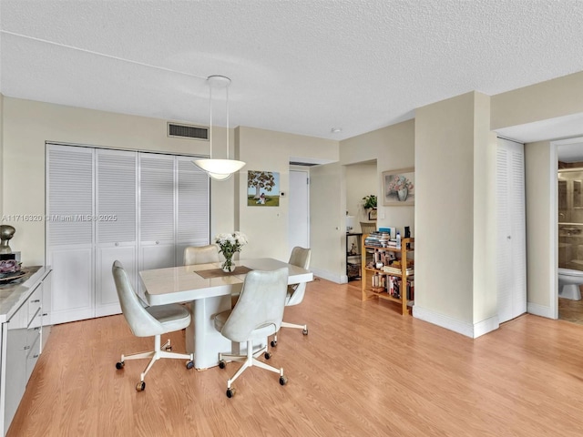 dining area featuring a textured ceiling and light hardwood / wood-style flooring