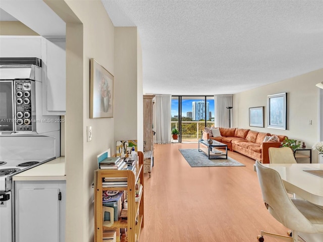 living room featuring wood-type flooring, a textured ceiling, and expansive windows