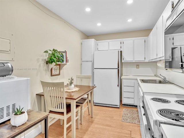 kitchen with white cabinets, white appliances, light hardwood / wood-style floors, and sink