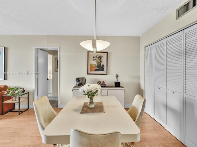 dining space with a textured ceiling and light wood-type flooring