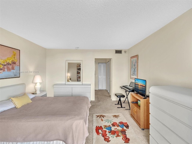 bedroom with a textured ceiling and light colored carpet