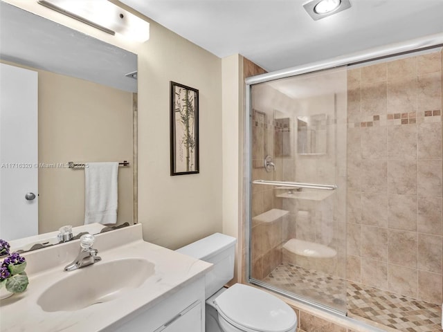 bathroom with vanity, a shower with shower door, and toilet