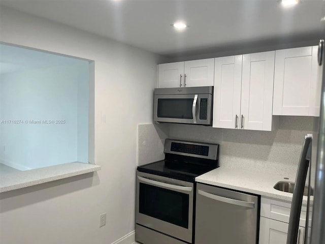 kitchen featuring light stone countertops, white cabinetry, appliances with stainless steel finishes, and tasteful backsplash