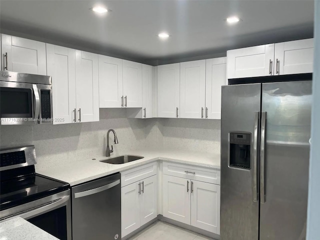 kitchen featuring white cabinets, stainless steel appliances, tasteful backsplash, and sink