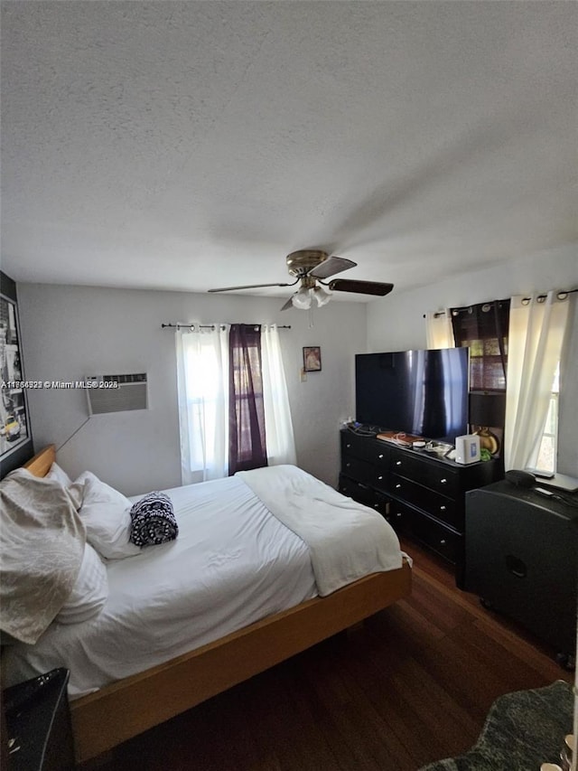 bedroom with a textured ceiling, ceiling fan, and dark wood-type flooring