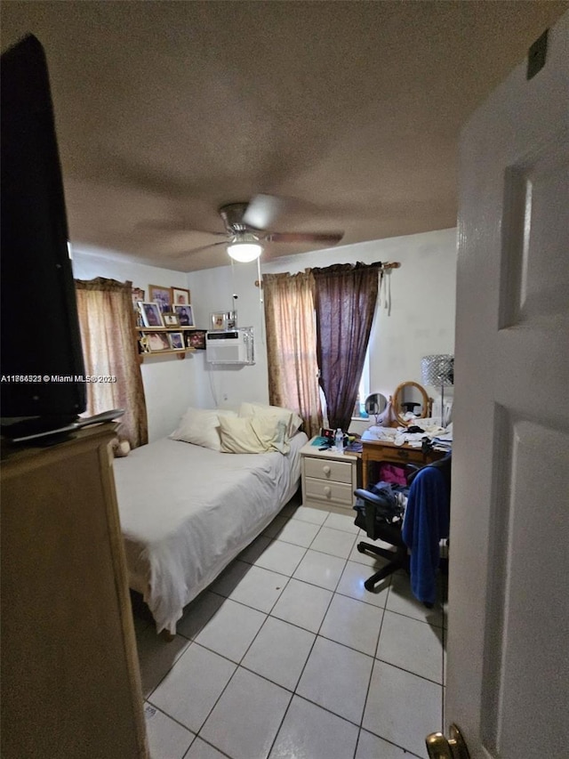 tiled bedroom with an AC wall unit, ceiling fan, and a textured ceiling