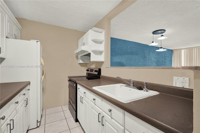 kitchen featuring black electric range oven, white refrigerator, sink, light tile patterned floors, and white cabinetry