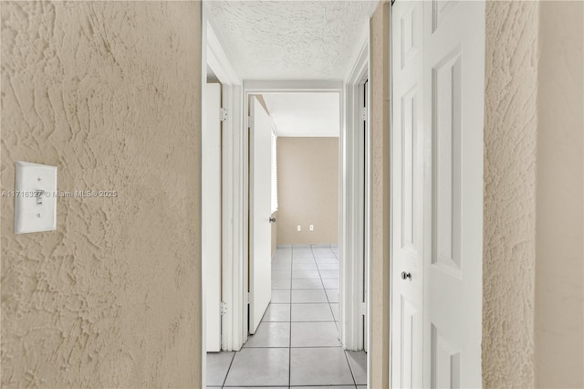 hallway featuring light tile patterned floors and a textured ceiling