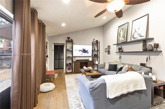 living room featuring ceiling fan, wood-type flooring, and lofted ceiling