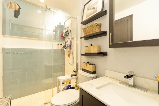 bathroom with a tile shower, vanity, and toilet