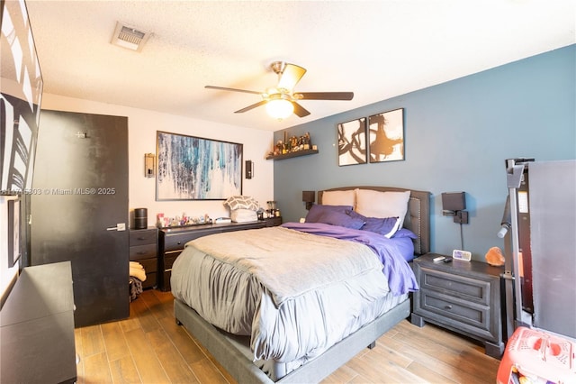 bedroom with ceiling fan, a textured ceiling, and light hardwood / wood-style flooring