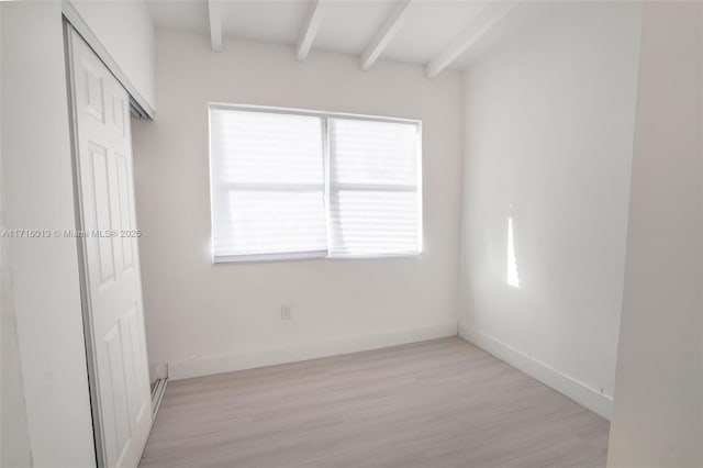 unfurnished bedroom with beam ceiling, light wood-type flooring, and a closet