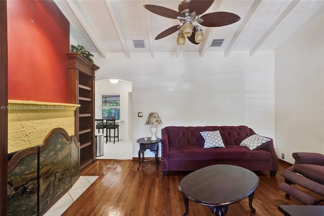 living area with beam ceiling, visible vents, and wood finished floors