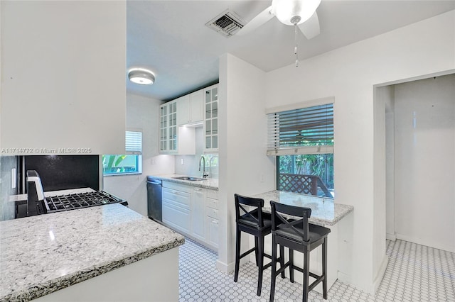 kitchen featuring visible vents, dishwasher, glass insert cabinets, light stone countertops, and white cabinetry