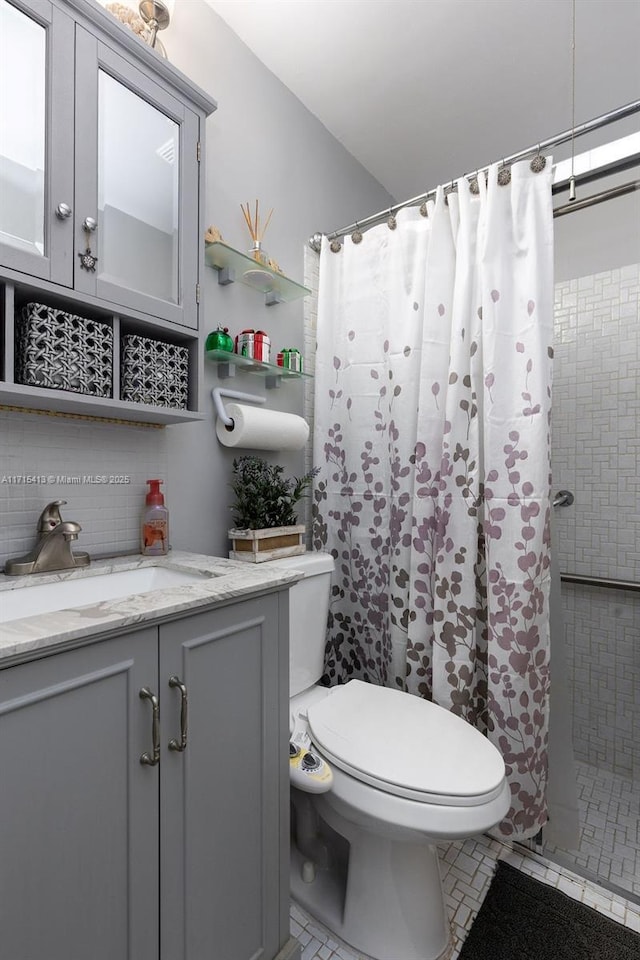 bathroom featuring curtained shower, decorative backsplash, vanity, and toilet