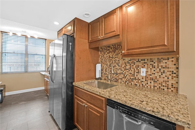 kitchen with light stone countertops, appliances with stainless steel finishes, backsplash, sink, and light tile patterned floors